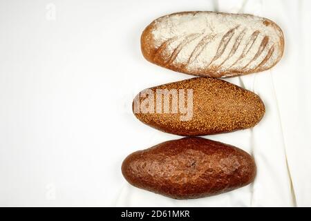 Various kinds of bread on white fabric surface. View from above Stock Photo