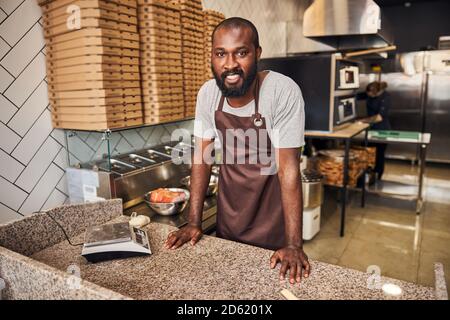 Cheerful young bearded chef working in pizzeria Stock Photo