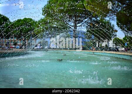 View of tiny drops of water gushing from a fountain. Blue water surface and many small drops of flying water. View into the stream inside the fountain Stock Photo