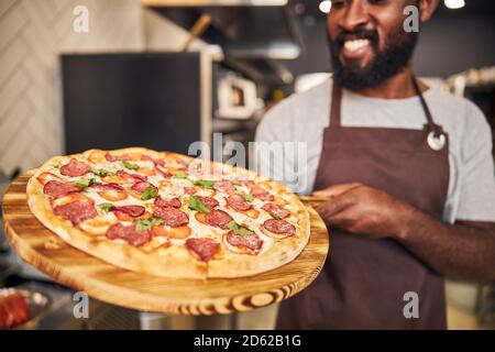 Joyful Afro American young man holding pepperoni pizza Stock Photo