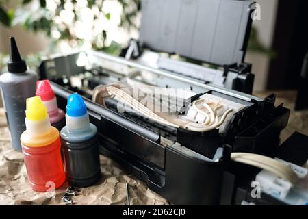 Refilling printer cartridges with multi-colored ink. Background Stock Photo