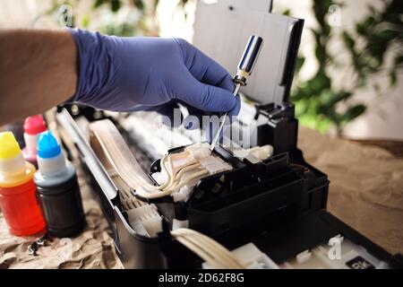 Refilling printer cartridges with multi-colored ink. Background Stock Photo