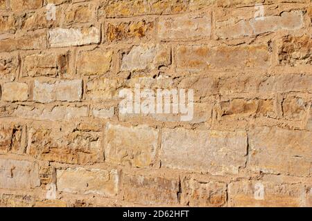Antique golden brown color stone wall background with worn texture in full sunlight, with copy space Stock Photo