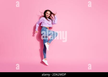 Full size photo of positive cheerful girl enjoy rejoice discount lottery win jump raise fists scream yes wear style stylish pullover isolated over Stock Photo