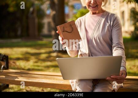 Content old lady using laptop on her knees Stock Photo