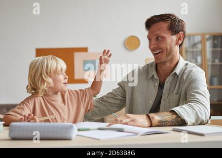 Happy mature father sitting at the table and having fun together with his son at home Stock Photo