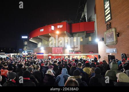 Football fans listen to a memorial service to commemorate the Munich plane crash beneath the Munich Clock outside Old Trafford Stock Photo