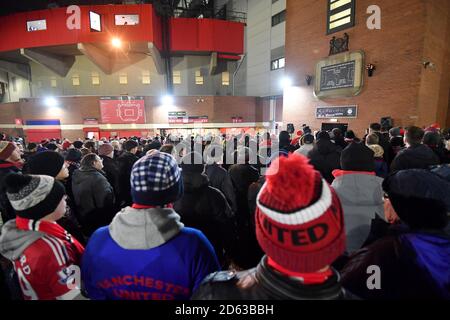 Football fans listen to a memorial service to commemorate the Munich plane crash beneath the Munich Clock outside Old Trafford Stock Photo