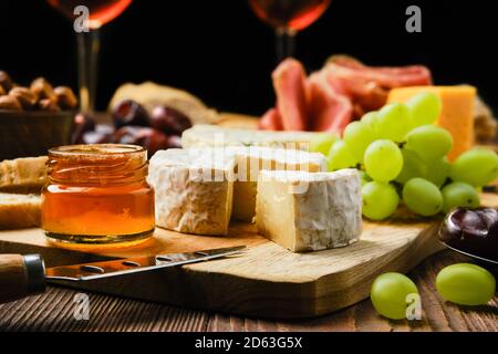Close up view of brie cheese on plate with snack for wine ( focus on foreground) Stock Photo