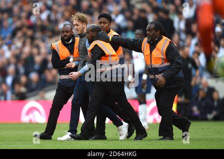 A pitch invader is assorted off the pitch by stewards  Stock Photo