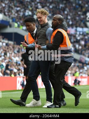 A pitch invader is assorted off the pitch by stewards  Stock Photo