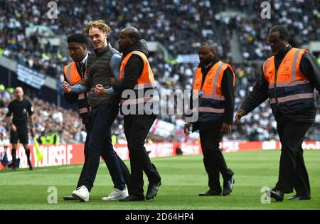 A pitch invader is assorted off the pitch by stewards  Stock Photo