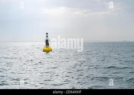 An Electric bollard light or buoy on the open sea in the esuary of the Thames, England, UK with the Red Sands Maunsell Forts in the distance Stock Photo