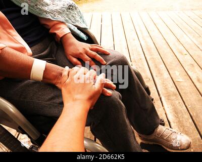 Close-up of a daughter supporting her disabled mother in a wheelchair. Stock Photo