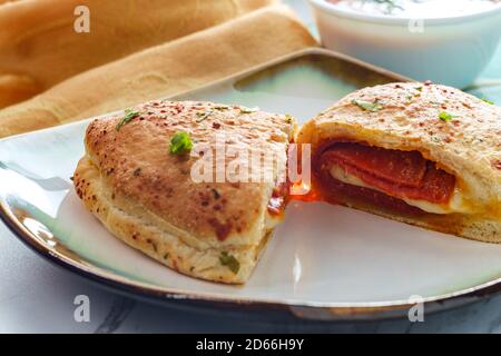 Italian pastry pepperoni and cheese calzone with tomato marinara dipping sauce Stock Photo