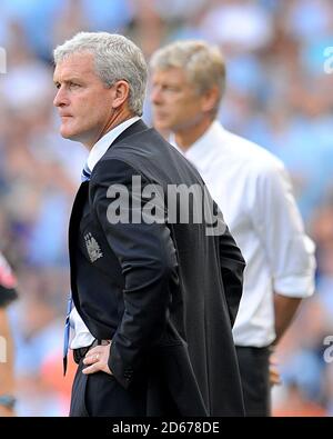 Manchester City manager Mark Hughes and Arsenal manager Arsene Wenger (background) on the touchline. Stock Photo