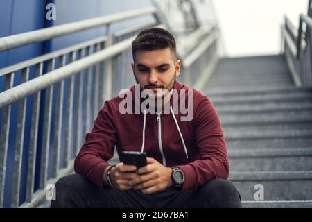 Male using his phone while sitting on a staircase Stock Photo
