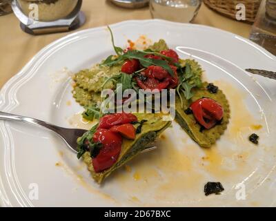 Eating pesto ravioli with tomatoes and arugula in a restaurant Stock Photo