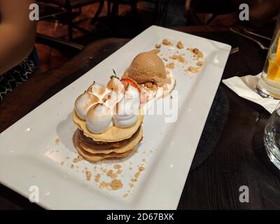 dessert made from layers of dulce de leche, cookies, meringue, and ice cream on the side Stock Photo