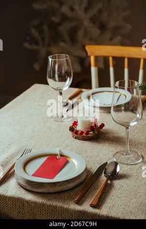 Homely christmas table setting, decorated with pine branches , pine cones, and rustic tablecloth surrounded by Nordic decoration and lights, with the Stock Photo