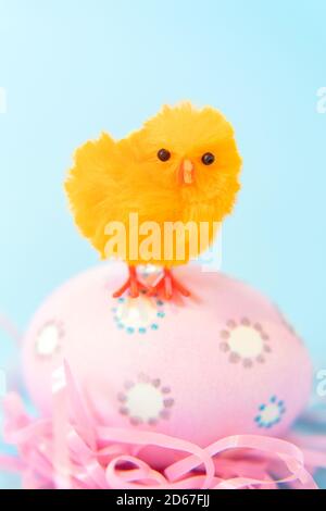 Orange Easter chick standing on pink egg Stock Photo