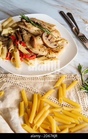 Creamy Italian chicken marsala with King oyster mushrooms and sundried tomatoes served over penne rigate pasta Stock Photo