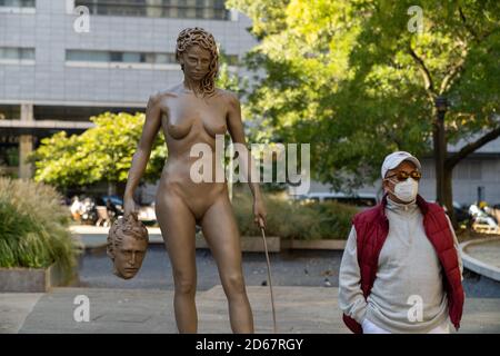 New York City, United States. 14th Oct, 2020. A man wearing a face mask poses for a photo next to the newly installed statue of 'Medusa With The Head of Perseus' by Argentine-Italian artist Luciano Garbati at the Collect Pond Park in New York City. Credit: SOPA Images Limited/Alamy Live News Stock Photo