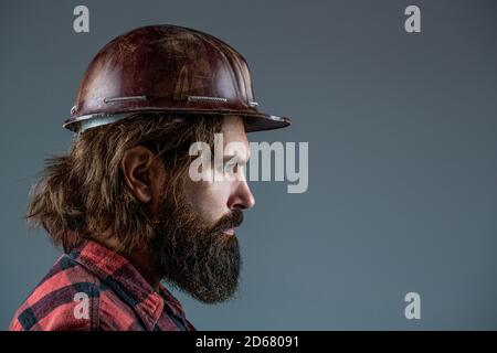 Man builders, industry. Builder in hard hat, foreman or repairman in the helmet. Building, industry, technology - builder concept. Bearded man worker Stock Photo