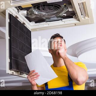 The repairman repairing ceiling air conditioning unit Stock Photo