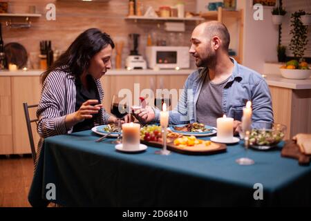 Woman surprised by marriage proposal from husband during romantic dinner. Kitchen during romantic dinner. Happy caucasian woman smiling being speechless Stock Photo