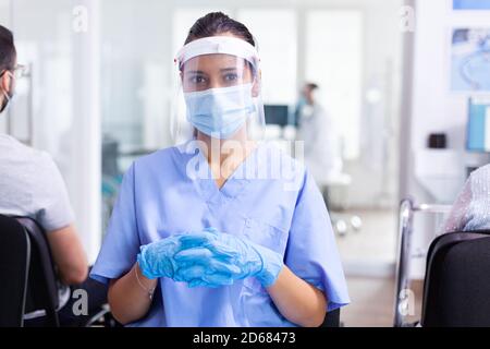 Medical staff in waiting area of hospital wearing surgical face mask as safety precaution against coronavirus global pandemic., Physician, epidemic, care, surgical, corridor. Stock Photo