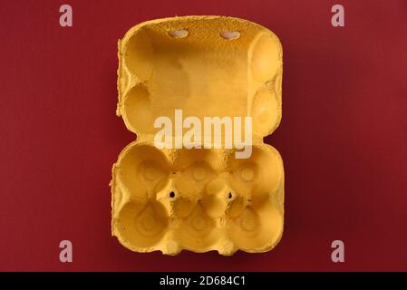 Empty yellow egg carton on a red background Stock Photo