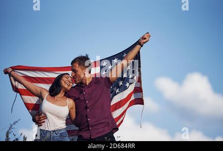 Feels freedom. Beautiful couple with American Flag have a good time outdoors in the field Stock Photo