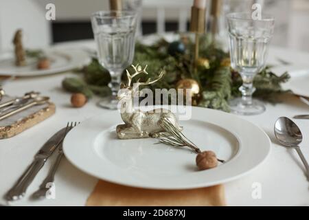 Christmas or New Years celebration party table setting. Plate with golden deer, cutlery and glasses Stock Photo