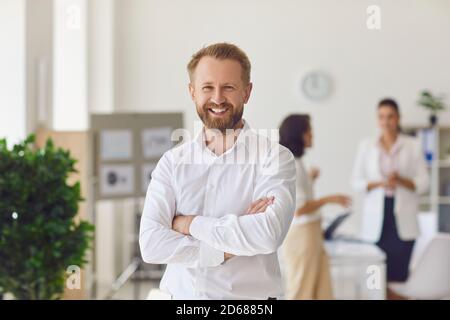 Happy successful businessman or company employee standing in office looking at camera Stock Photo