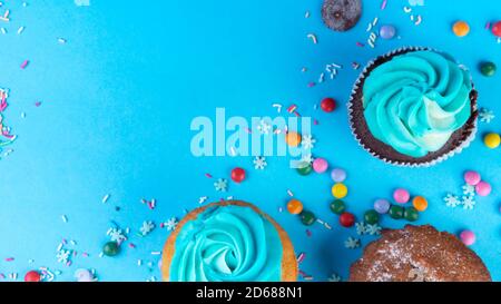 Gourmet chocolate and vanilla cupcakes topped with blue buttercream frosting, decorated with sprinkles on blue background, copy space, easter, christm Stock Photo