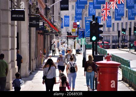 People walking on Regent Street with Thank You Our Heroes flags and social distancing street barriers, London. Stock Photo