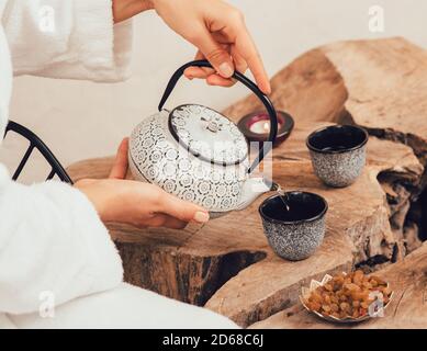 Woman pours wellness tea in spa after massage. Relaxation tea Stock Photo