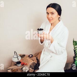 Portrait of a healthy 35-year-old woman in bathrobe drinking tea and enjoying spa day Stock Photo