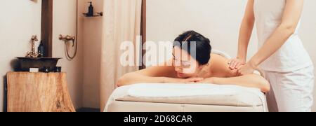 Beautiful woman getting a back massage. Beautiful mixed race woman relaxes while massaging her body. Stock Photo