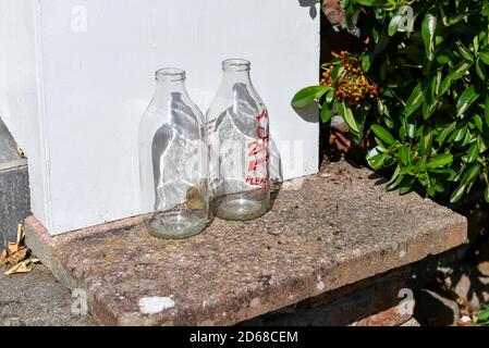 Close up of clean glass traditional empty milk bottles bottle outside a house on a doorstep England UK United Kingdom GB Great Britain Stock Photo