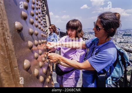 A teacher helps a student feel the rivets on the Eiffel Tower. Party from Edinburgh Blind School visit Paris and the Louis Braille Institute and Institute Nationale des Jeunes Aveugles. 23 June 1993. Photo: Neil Turner Stock Photo