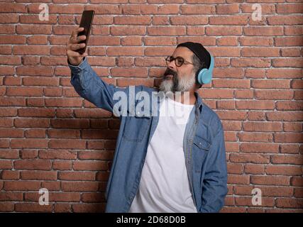 Caucasian male using his phone and listening to music by headphones Stock Photo