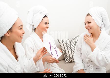 Gift card certificate at the spa. Women give a certificate to their girlfriend, spa services, body treatments. Women in bathrobes enjoying relaxing at Stock Photo