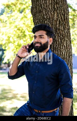 Young Indian man talking by phone in the park. Stock Photo