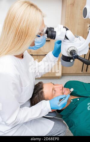 Dentist while working. Treatment teeth to a patient using a microscope at dental clinic. Modern stomatology technology Stock Photo