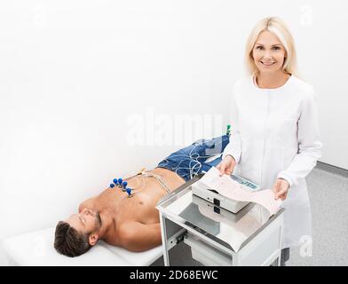 Mature doctor cardiologist holding electrocardiogram results of patient. Heart disease diagnostic. Stock Photo