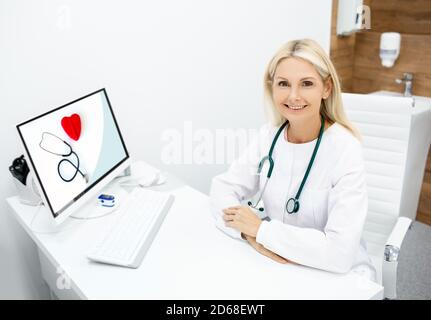 Portrait of mature doctor general practitioner at her workplace. doctor with stethoscope, sitting at a medical office Stock Photo