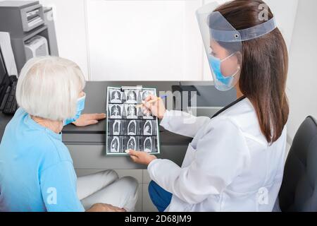 Pulmonologist showing an elderly patient a CT scan of her lungs. Pneumonia, coronavirus, lung disease Stock Photo