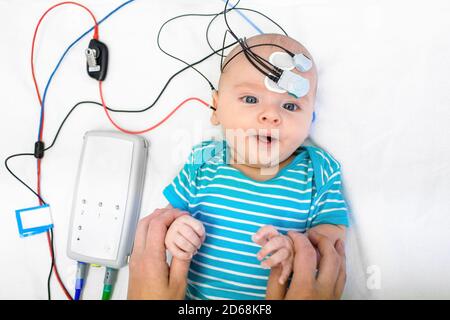 Newborn hearing screening and diagnosis at the hospital. Baby having hearing screening with special electrodes on his head and ear Stock Photo
